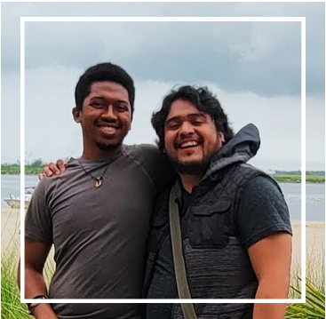 Jonny and Ricky smiling together outdoors by the water